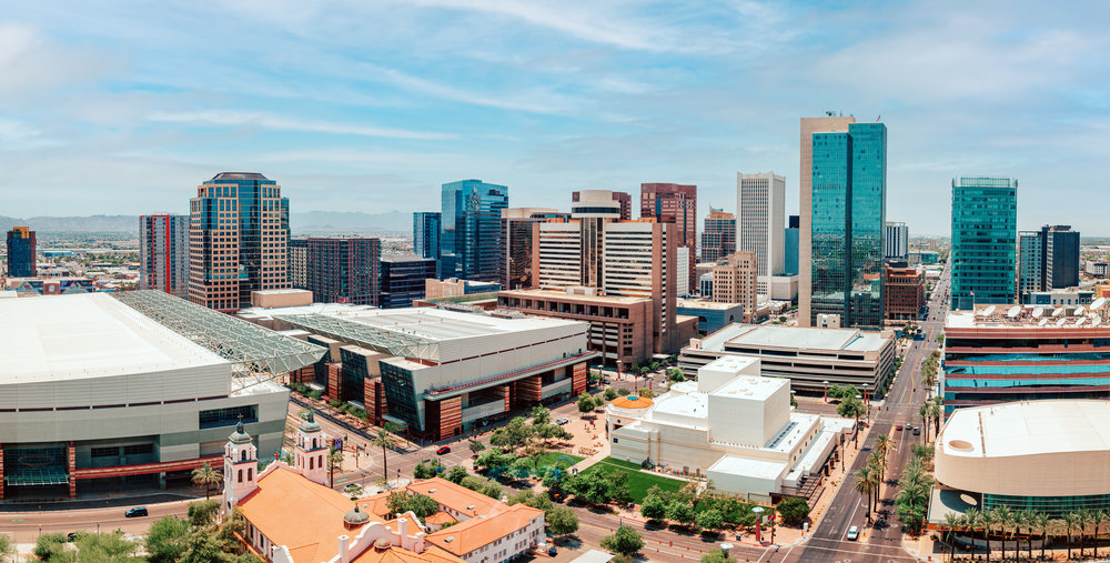 Downtown cityscape with tall modern buildings under a blue sky, seen from an elevated viewpoint.