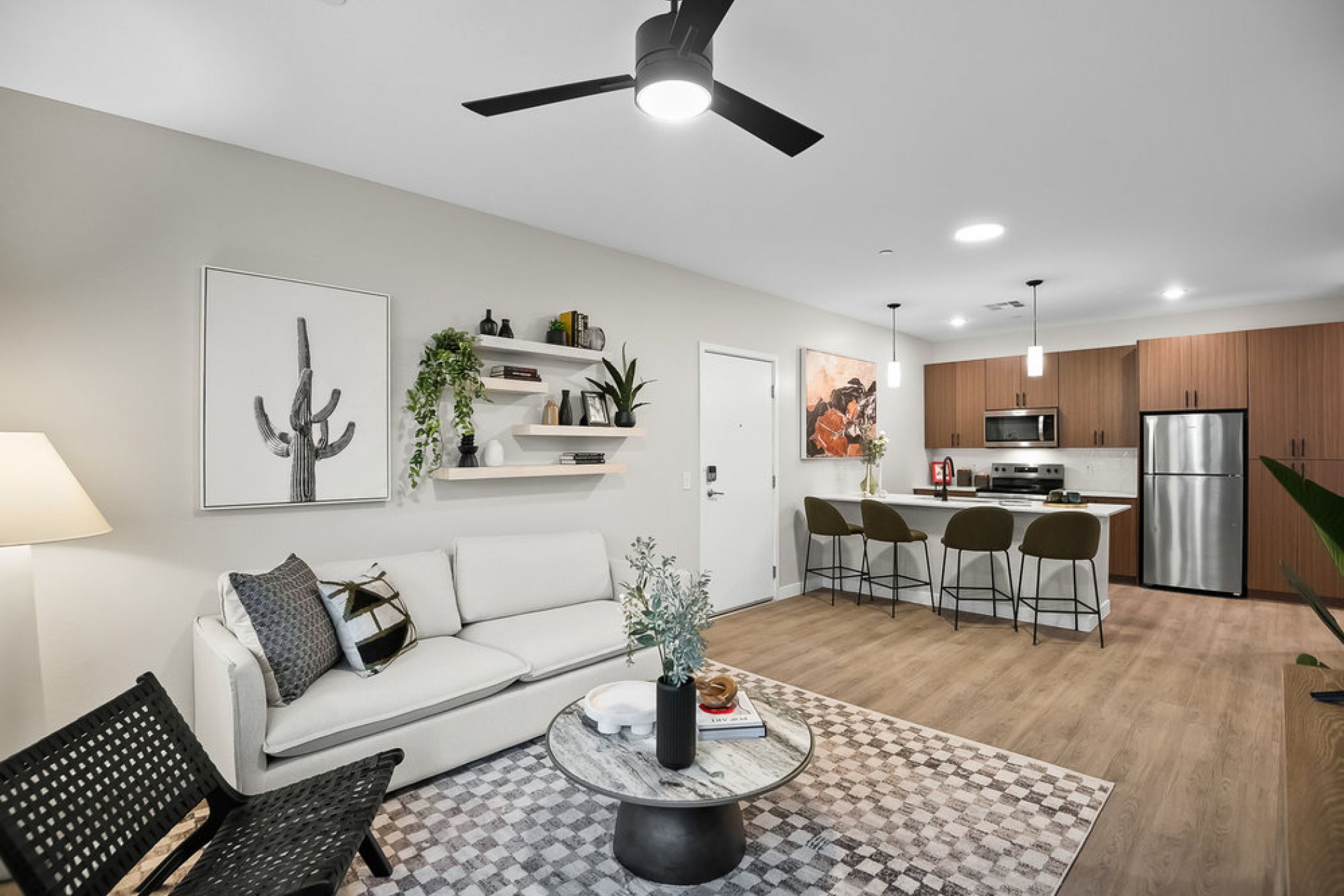 Modern living room and kitchen with neutral tones, a white sofa, plants, and wooden accents.